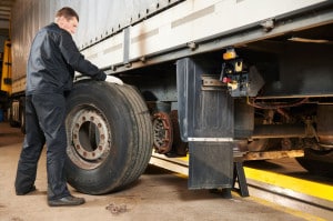 Truck repair service. Mechanic works with tire in truck workshop