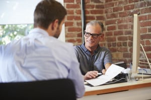 Businessman Interviewing Male Job Applicant In Office